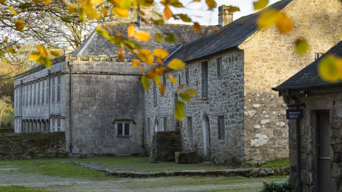 The North facing front of Godolphin House, Cornwall with autumn leaves in the foreground.
